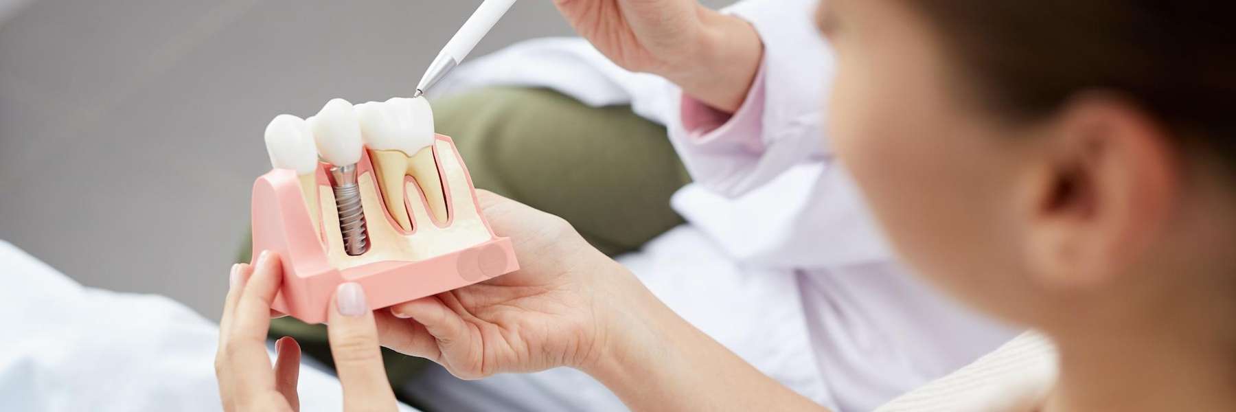 Patient holding a model of a dental crown with an implant in Annapolis, MD