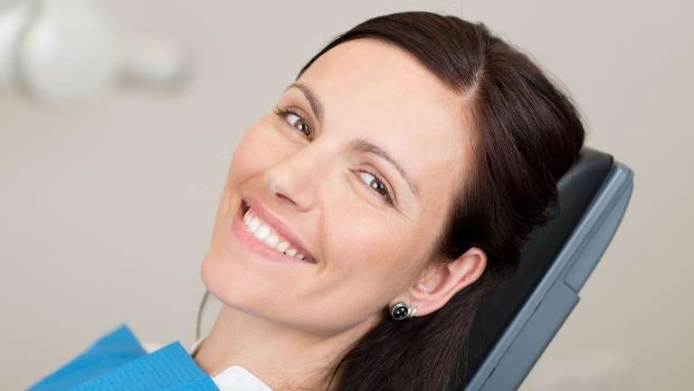Lady smiling on dental chair after getting dental crowns in Annapolis, MD