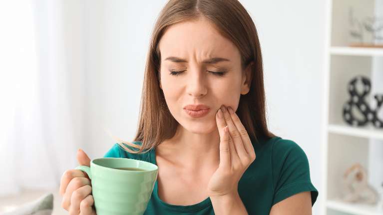 Lady holding her jaw in pain due to a dental emergency in Annapolis, MD